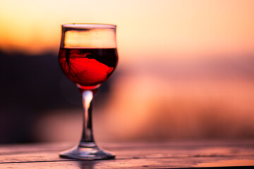 Glass with red wine. Glass on a blurred background. A medieval castle reflected in a glass. Evening time at sunset