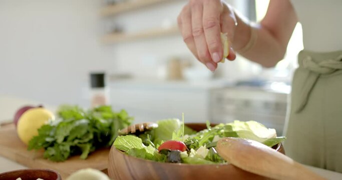 A person is sprinkling herbs over a salad