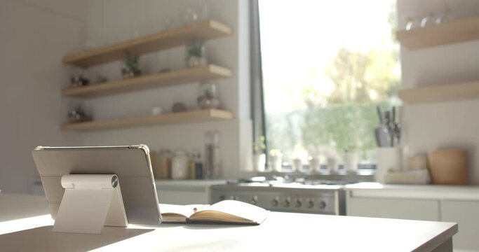 A tablet and notebook rest on a kitchen counter with copy space