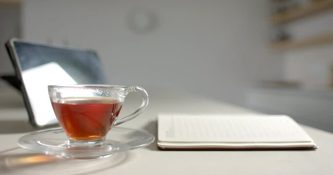 A cup of tea sits beside an open notebook on a desk with copy space