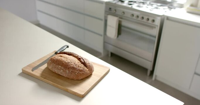 A loaf of bread and a knife rest on a cutting board