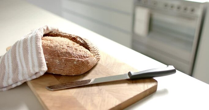 A loaf of bread rests on a wooden board, ready to be sliced