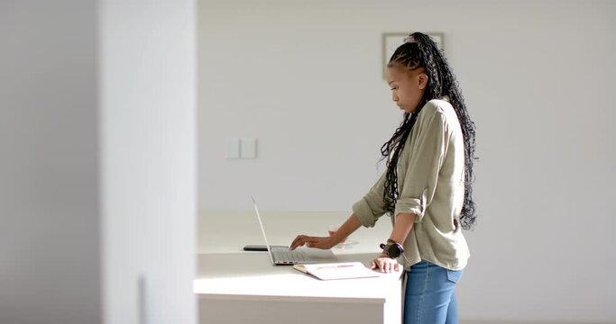 A young African American woman is working on her laptop with copy space in the kitchen at home