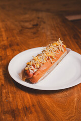 Top view of a hot dog covered in french fries on top of a wooden table.