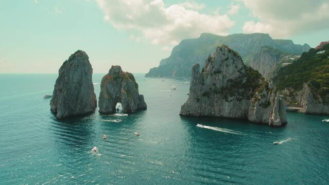 The iconic Faraglioni rocks of Capri surrounded by azure sea waters. Summer seascape in Italy.