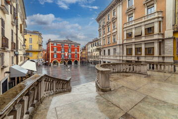 Fototapeta na wymiar Mondovi, Italy: St. Peter's Square, view of the historic buildings decorated with arcades and the square paved with stone slabs after rainy day