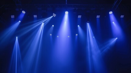 Bright blue lights illuminating the stage from above in a concert hall setting, creating a lively...