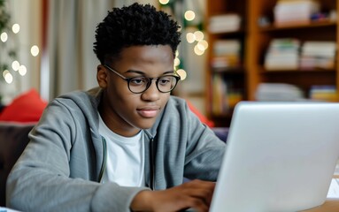 Black teen boy using laptop at home. young male with curly hair enjoying technology in a cozy home setting