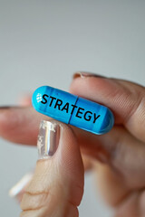 Fingers holding a blue mini pill with text "STRATEGY"