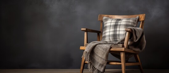 A wooden chair with a plaid pillow and blanket sits on the hardwood flooring, adding a cozy touch to the rooms decor - obrazy, fototapety, plakaty