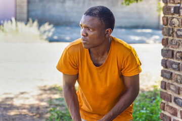 african man in the street sneaking into a yard, in a sunny summer day
