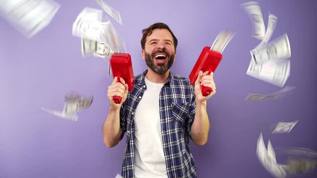 Excited man using a couple of money guns to throw money into the air and give it all away