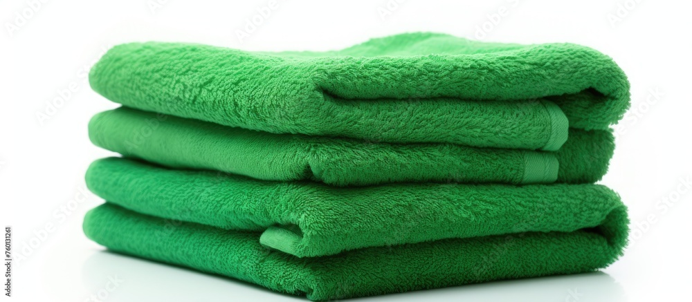 Poster three green towels made of natural material are neatly stacked on top of each other on a white backg