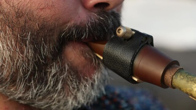 Close-up of a man playing a saxophone mouthpiece