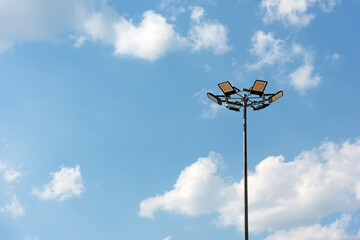 Tall metal lamppost with lamps in a circle against a blue cloudy sky - street lighting, LED lamps,...