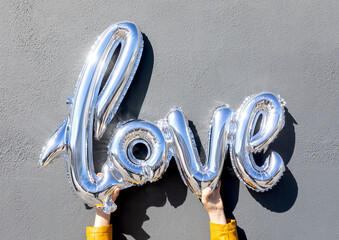 Holding silver balloon letters spelling love