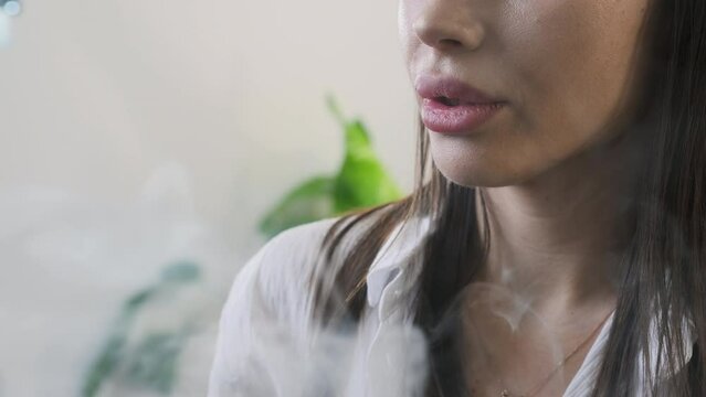 Gentle plumes of vapor escape woman plump full lips. Vapor mingles with surrounding air helps lady gather thoughts among day activities