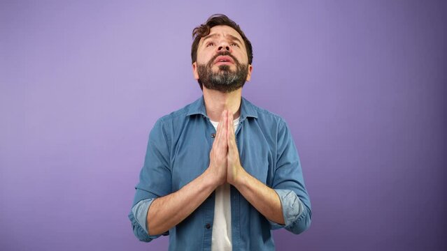 Hopeful man with hands clasped looking upwards and making a wish