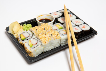 Sushi to go in a black takeaway box with wooden chopsticks on white background