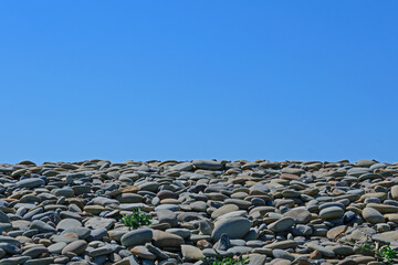 Gray stones on the seashore against the blue sky