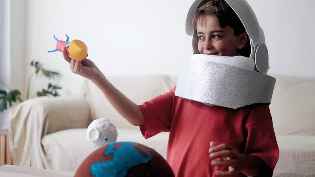 Astronaut child playing with rocket ship traveling in space at home. Happy boy playing and exploring galaxy
