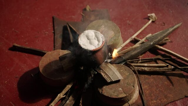 Sri Lankan housewife performs traditional milk boiling over open flame, prosperity. Milk overflows in clay pot during Vesak celebration, honoring Buddha. Cultural heritage, spirituality blend ritual.