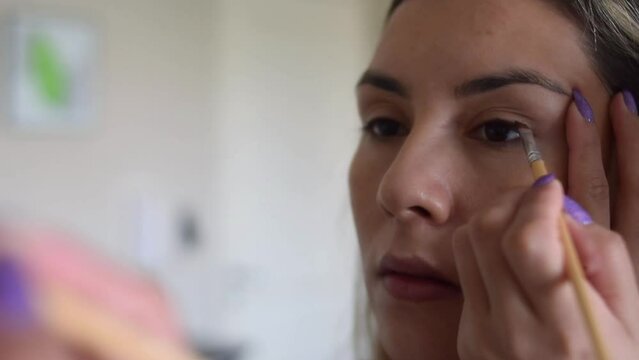 close-up woman putting on makeup in front of a mirror