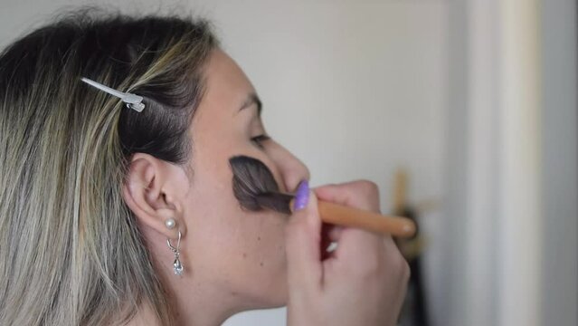 close-up woman putting on makeup in front of a mirror