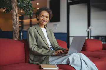 Woman on red couch with laptop in comfortable interior design setting 