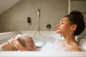 A woman is enjoying a bath in a foamy tub filled with water in the bathroom