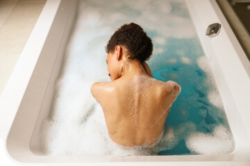 Man leisurely bathing in foamy water in bathtub for fun and recreation