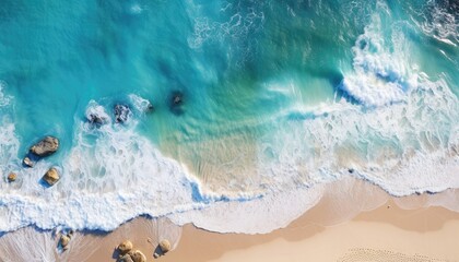 Obraz premium Aerial view of a paradise beach where the sea waves break on the shore. Top view of a beautiful sandy coast with turquoise blue water and white foam on sunny day. Summertime, traveling, holidays.