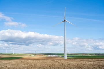 éolienne dans les champs avec une centrale gaz en arrière plan