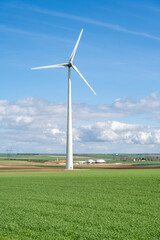 éolienne dans les champs avec usine de biogaz en fond