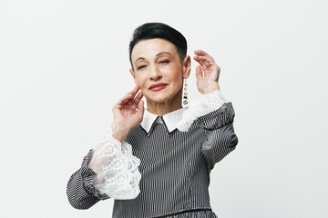 Elderly woman in elegant black and white dress covering her ears with hands in distress