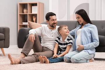 Pregnant woman spending time with her son and husband at home. Happy family