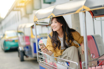 Attractive beautiful tourist woman or traveler woman sitting on tuk tuk taxi exploring the city on...