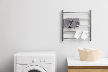 Heated towel rail with socks on white wall in bathroom, space for text