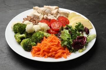 Balanced diet and healthy foods. Plate with different delicious products on black table, closeup
