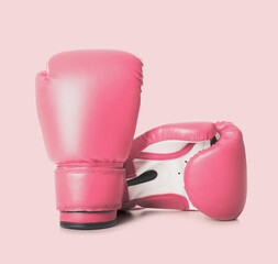 Fight against breast cancer. Pair of pink boxing gloves on color background