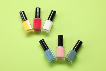 Obraz premium Colorful nail polishes in bottles on green background, flat lay