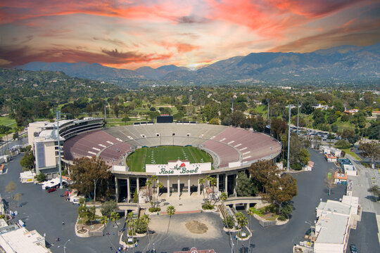 aerial shot of the Rose Bowl Stadium with lush green trees, plants and grass, homes and majestic mountains in Pasadena California USA