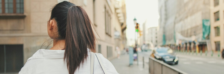 Young woman walks down the street and looks around, Back view, Panorama