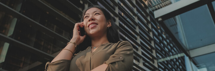 Young businesswoman talking on smartphone on business center background, Panorama