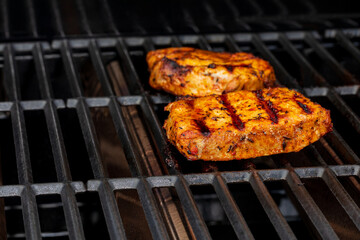 Pork chops cooking on gas grille. Outdoor BBQ, food safety and cooking temperature concept.