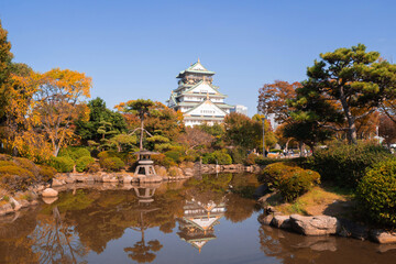 Osaka Castle building with colorful maple leaves or fall foliage in autumn season. Colorful trees, Osaka City, Japan. Architecture landscape background. Famous tourist attraction.