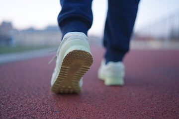 Close-Up of Feet Walking on Red Running Track