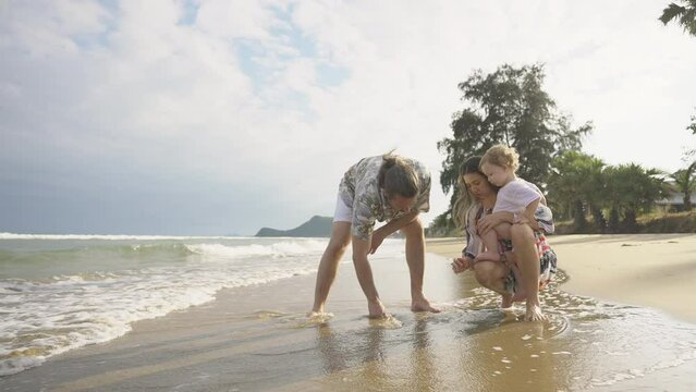 Happy Caucasian family enjoy and fun outdoor lifestyle travel nature at the sea on summer beach holiday vacation. Parent and little child boy walking and playing together on tropical island at sunset.