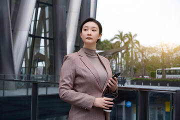 Confident Businesswoman Holding Phone Outdoors