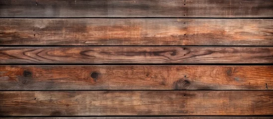 Fototapeten A closeup image showcasing a beautiful hardwood wall with a brown wood stain, creating a captivating pattern of rectangles resembling brickwork, set against a blurred background © AkuAku